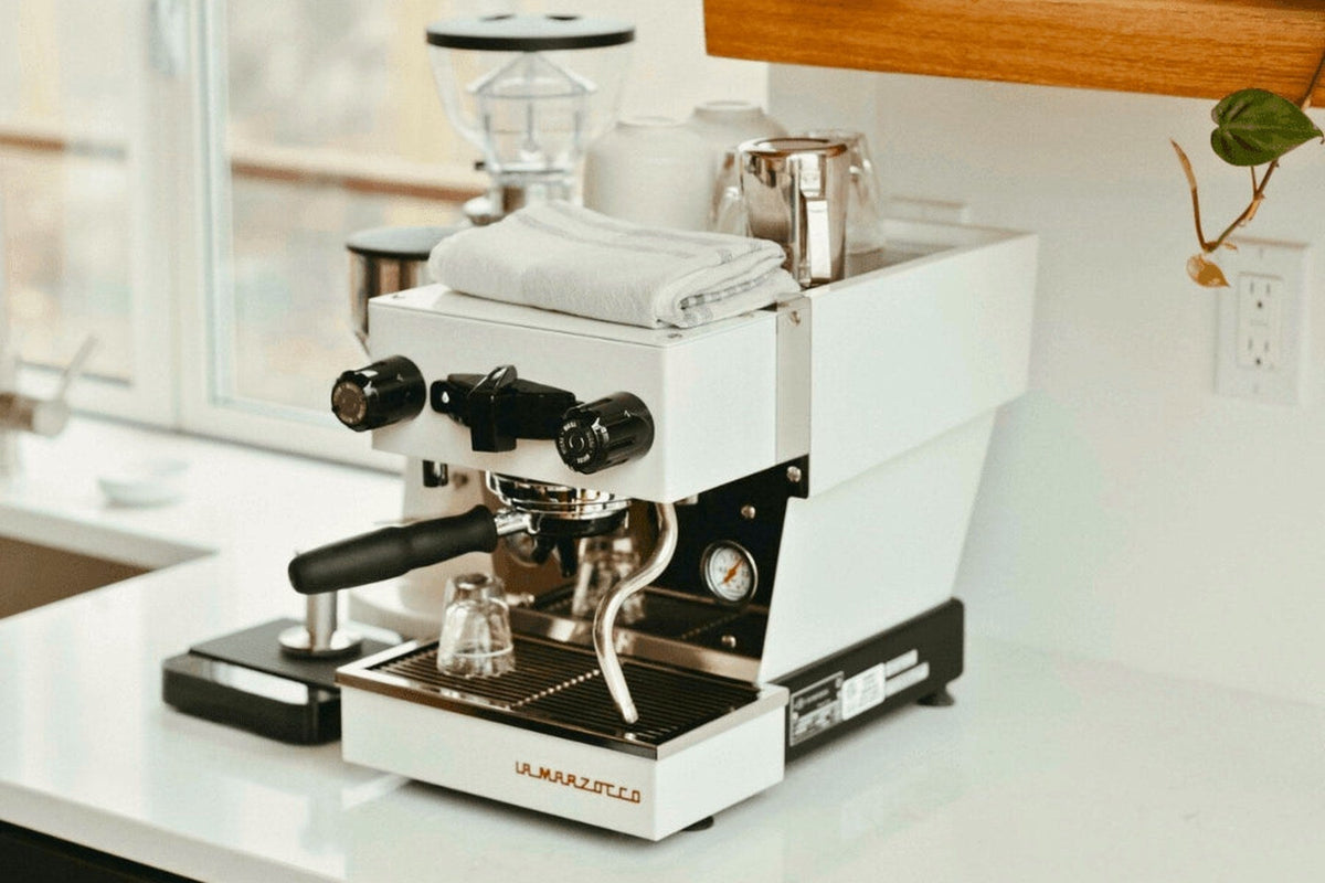 La Marzocco Linea Micra bianca su un piano di cucina, con il macinacaffè alle spalle e la luce che entra dalla finestra