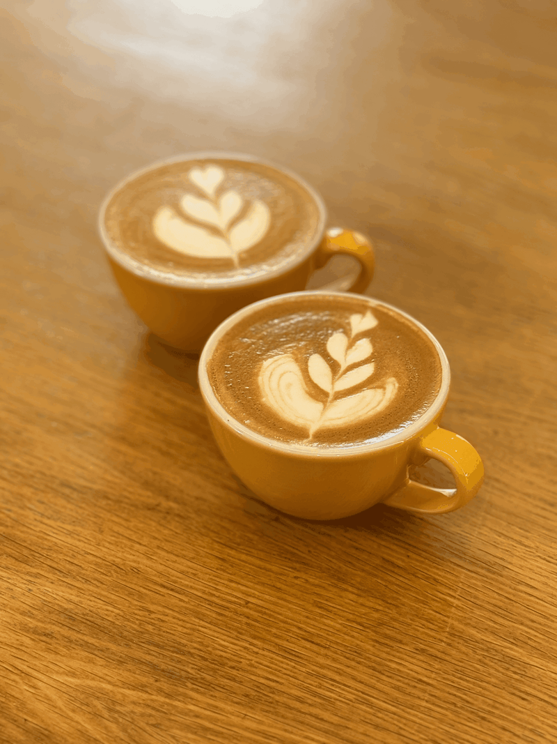 Due cappuccini con latte art su un tavolo di legno